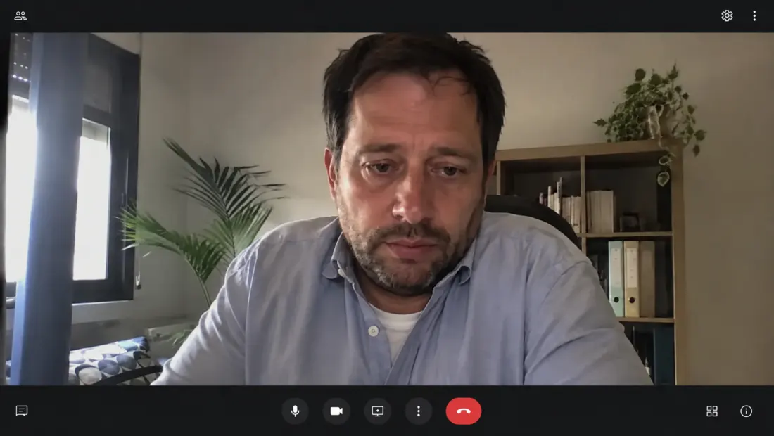 Fotogramma di una videochiamata: uomo in camicia con testa in avanti e spalle chiuse davanti allo schermo